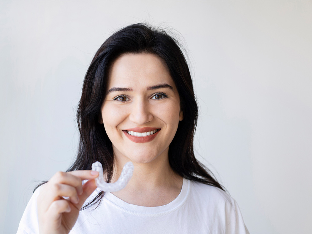 Woman Holding Invisalign Clear Aligner