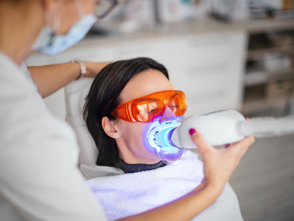 Woman having her teeth whitening professionally with a light activated solution
